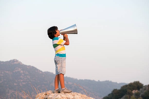 Child on a mountain top holding a megaphone