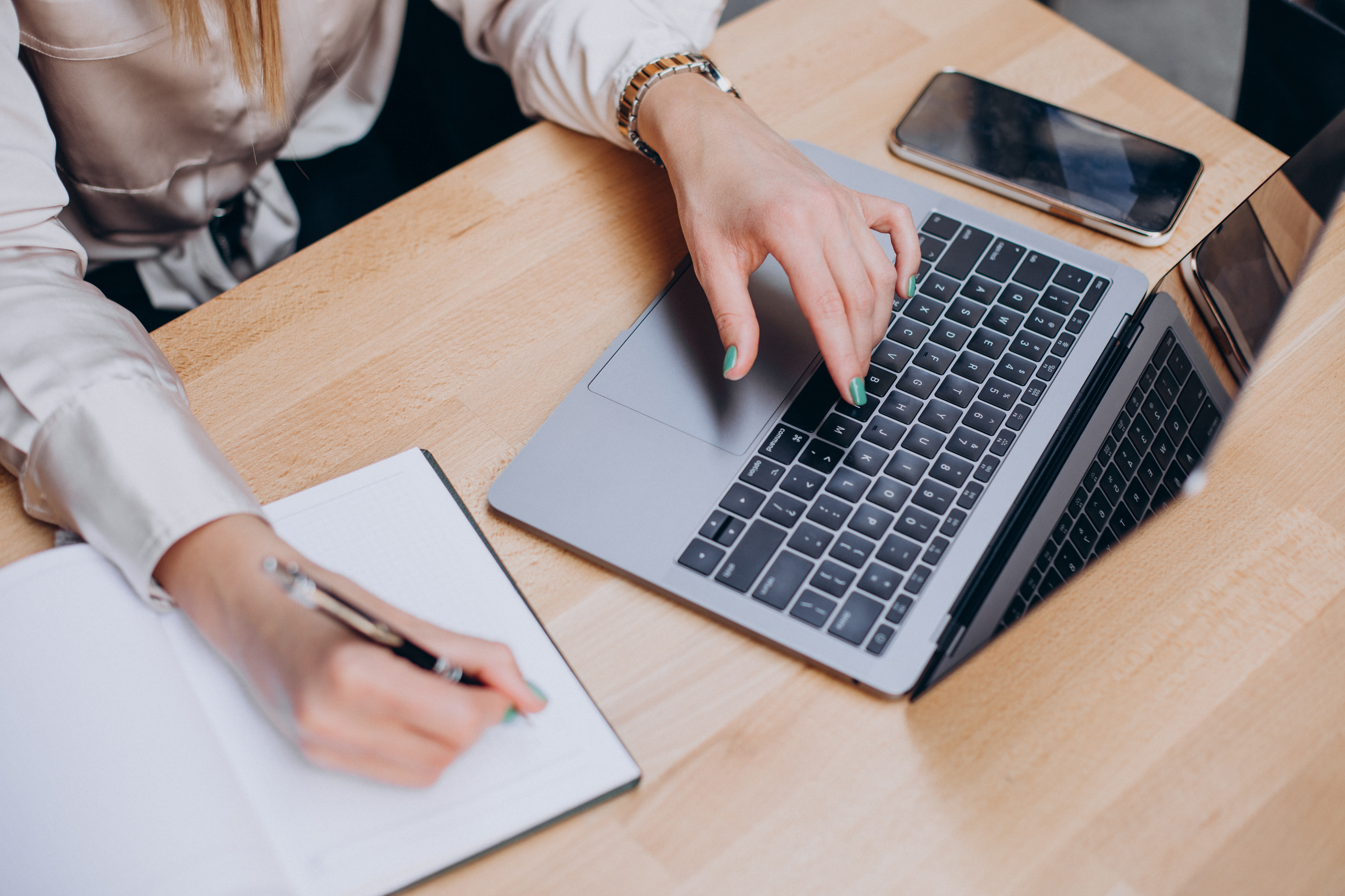 this is an image of hands at a computer with a notebook