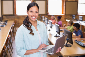 Image of teacher in classroom holding a laptop