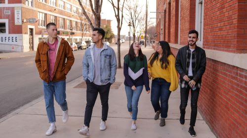 A group of young people walking down a sidewalk.