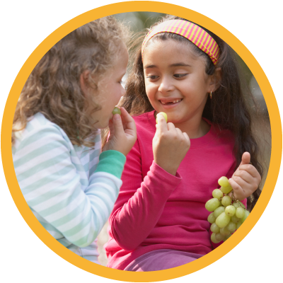 Two young children snacking on green grapes