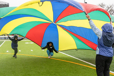 Students playing under colorful parachute