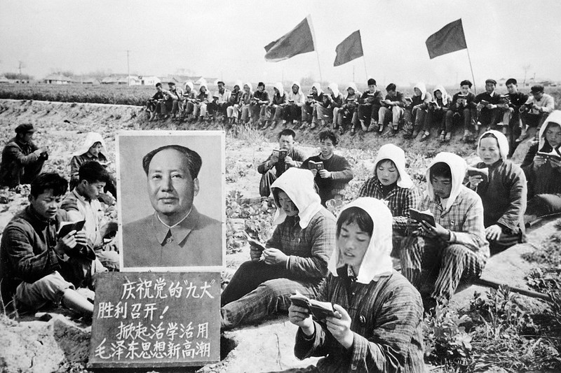 Chinese peasants gather in May 1969 in a field in Hungching region around a huge portrait of Chinese communist leader Mao Zedong (1893-1976), as they read collectively 'Little Red Book' of quotations from Mao's works