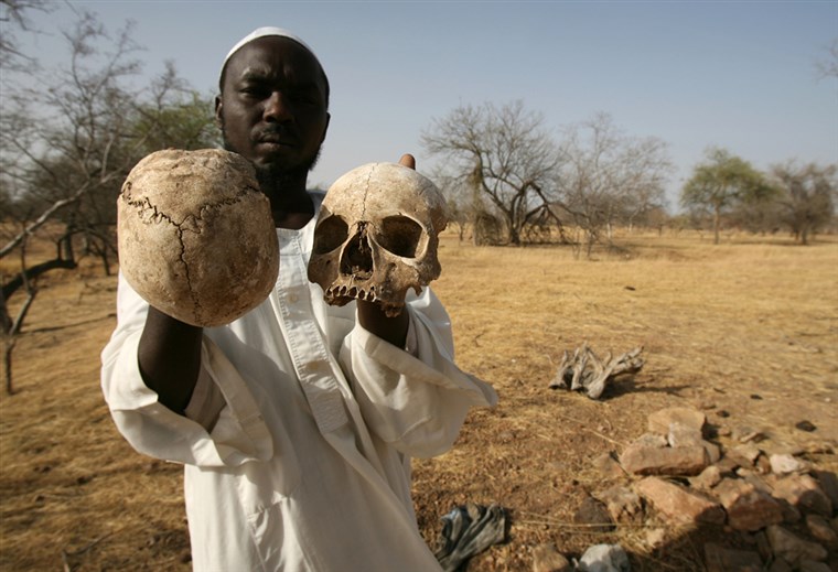 Sudanese Darfur survivor Ibrahim holds human skulls at the site of a mass grave on the outskirts of the West Darfur town of Mukjar, Sudan. Helps to refute the denial by Khartoum.
