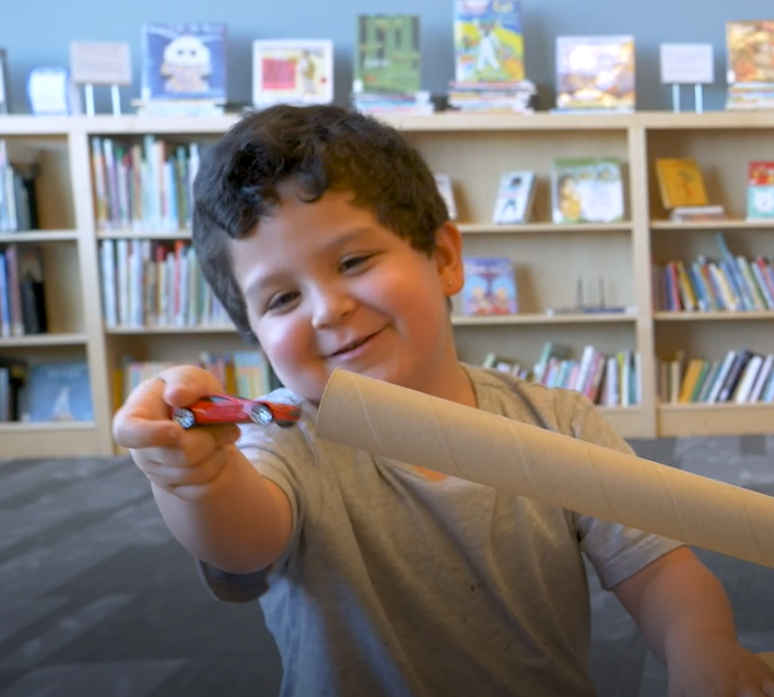 Young boy playing with a cardboard tube in a classroom
