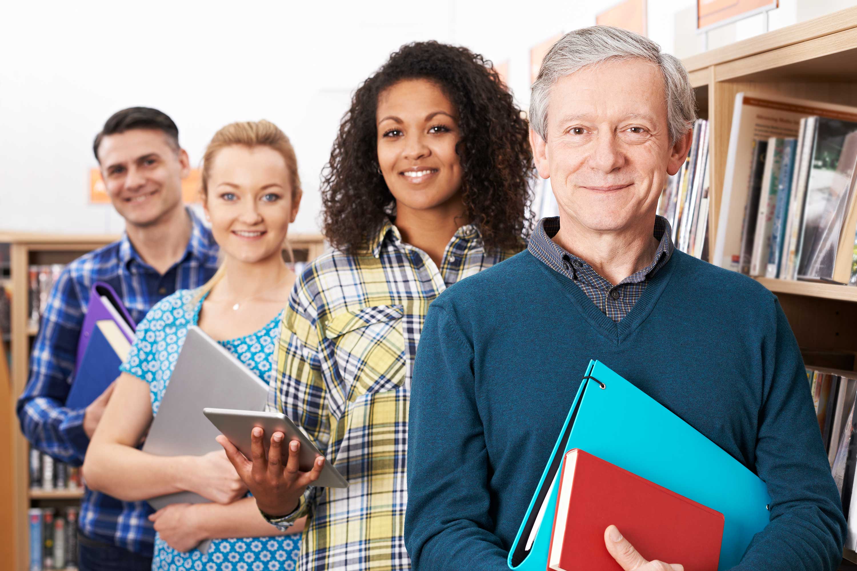 Diverse group of educators standing in line holding books and tablets. 