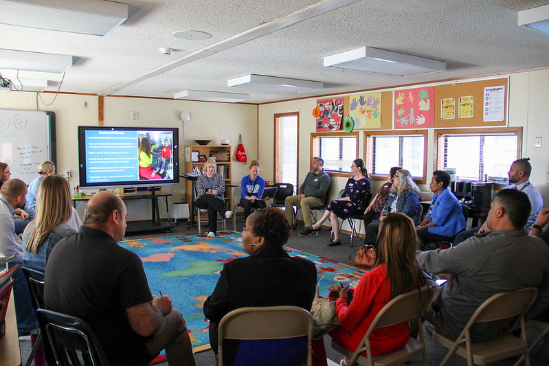 A group of adults in a classroom looking at a presentation.