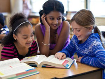 Kids smiling while reading a book. 