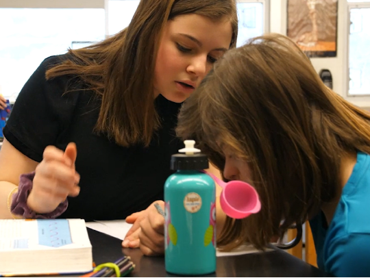 A female student peer mentoring another female student with a disability.