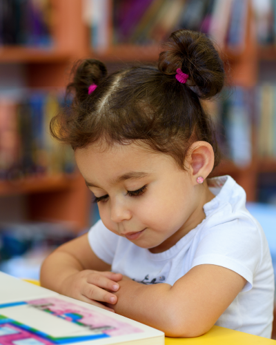 Young child looking at a book in a library setting