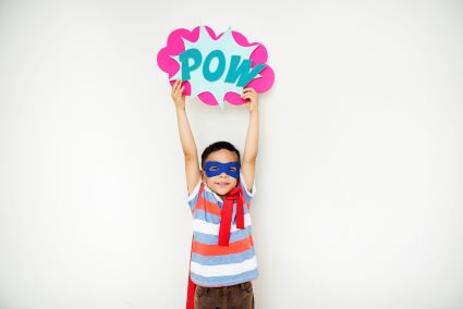 Kid holding a POW sign dressed as a superhero