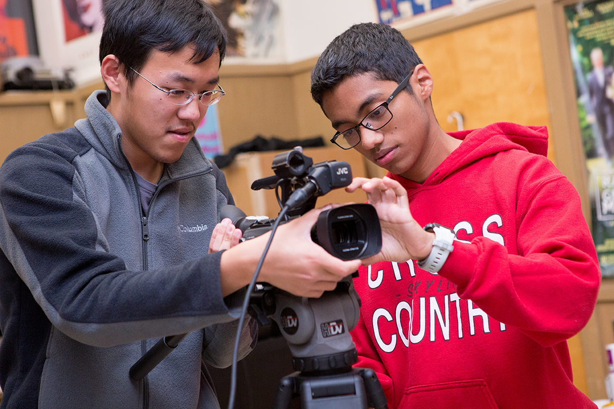 An adult and student work together on a piece of video recording equipment