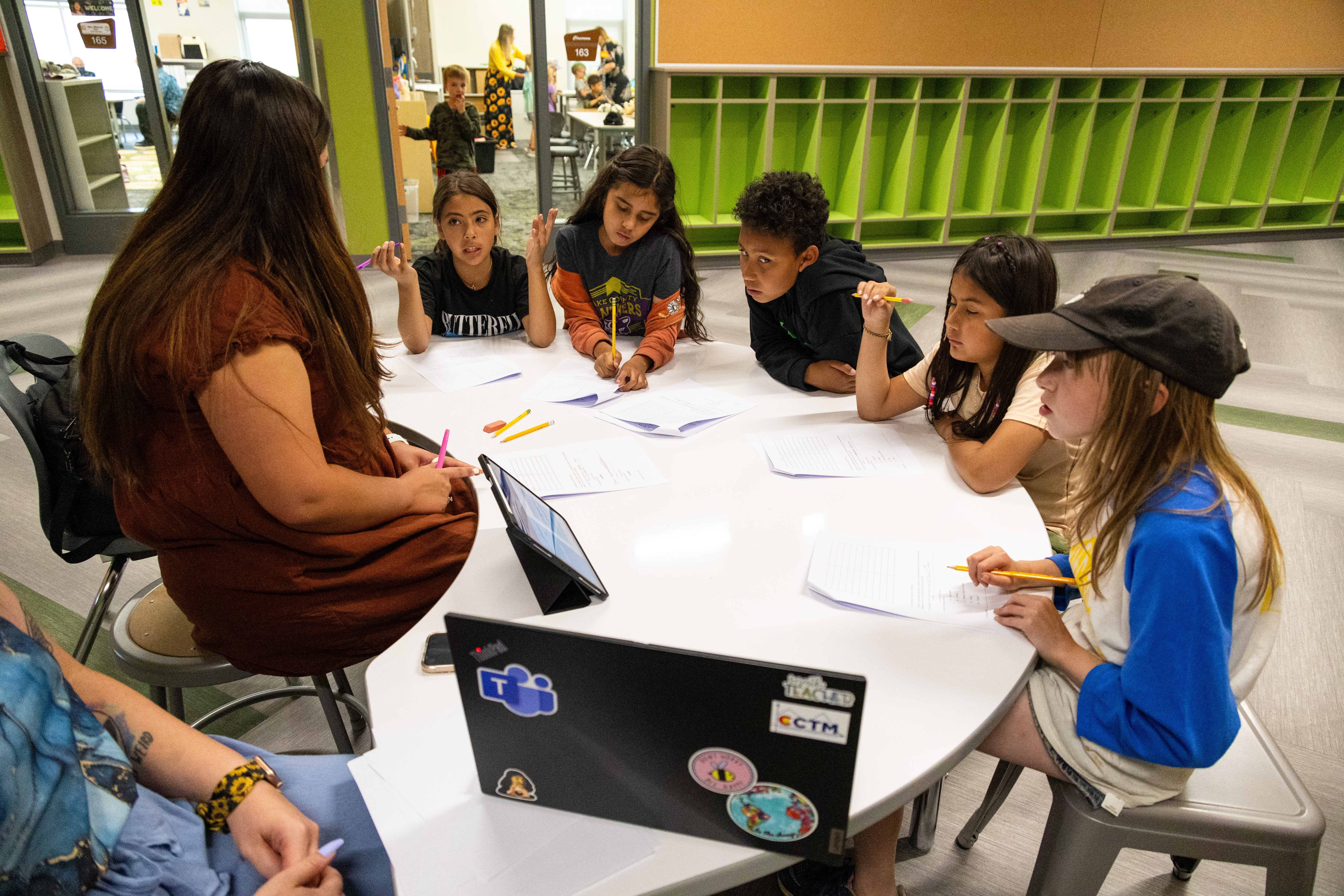 Students sitting at a table in a school hallway. 